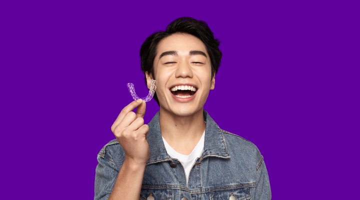 A guy with black hair holding up a teeth straightening kit