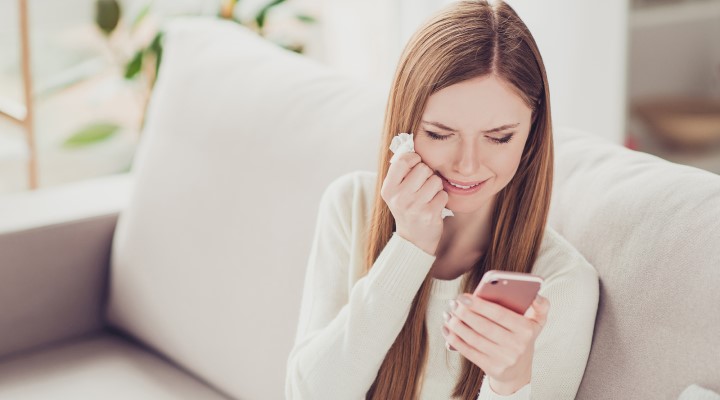 woman crying while looking at mobile phone