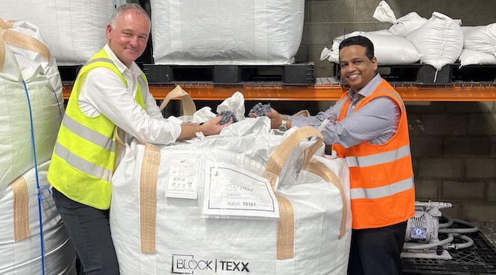 BlockTexx co-founder Graham Ross and Elk head of sustainability Dr Vaibhav Gaikwad standing on either side of a bale of cotton in a warehouse.