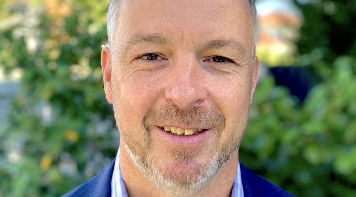 close-up headshot of Graeme Moore, head of Salomon ANZ in blue collared shirt against green blurred bush