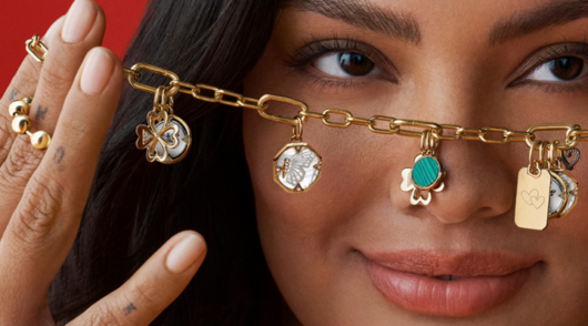 A model holds a Pandora charm bracelet up in front of her face