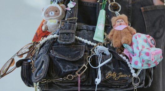 An image of a young woman with a handbag covered in accessories and bag charms.