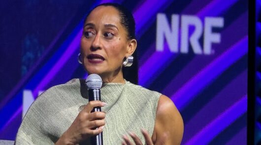 An image of actress and brand founder Tracee Ellis Ross holding a microphone and speaking at a business conference.