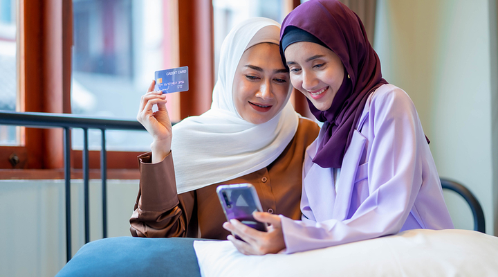 Two women wearing hijabs shopping on a smartphone