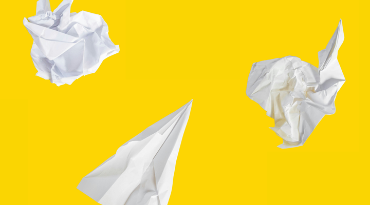 paper airplane and crumpled balls of paper against a yellow background