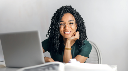 a young woman sitting at a laptop and smiling