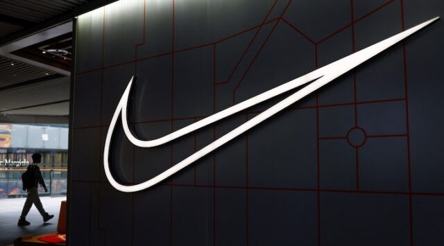 A person walks past a Nike store