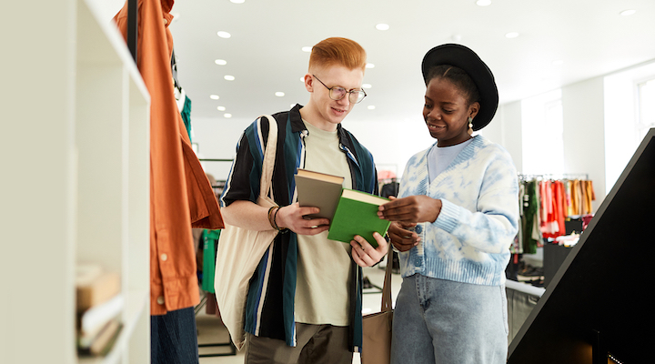 Two Gen Z shoppers browsing books at an indoor shopping center.
