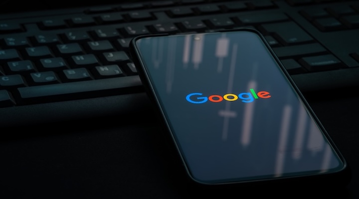 Google logo on smartphone screen laying on computer keyboard