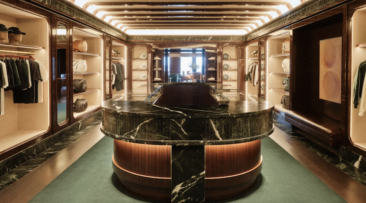 An interior shot of a Kith Ivy location in New York, featuring a large marble table and several shelves of clothes.