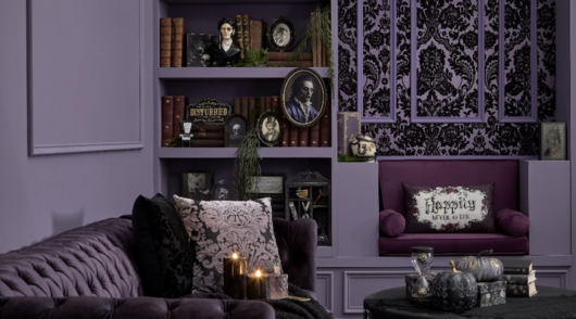 A dark purple living room-style set-up decorated with an assortment of Halloween-themed decorations.