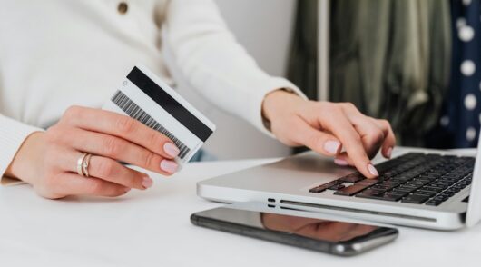 Person using a laptop and holding a credit card