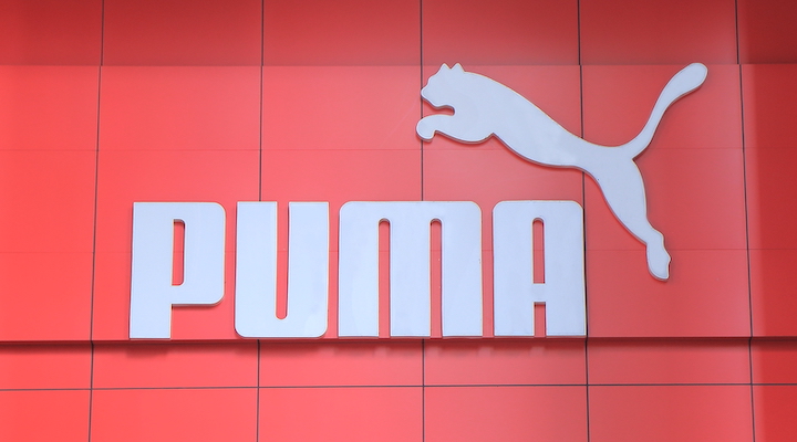 A white Puma logo embossed against a bright red wall.