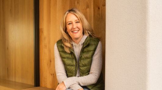 REI CEO Mary Beth Laughton seated in front of a wooden wall.