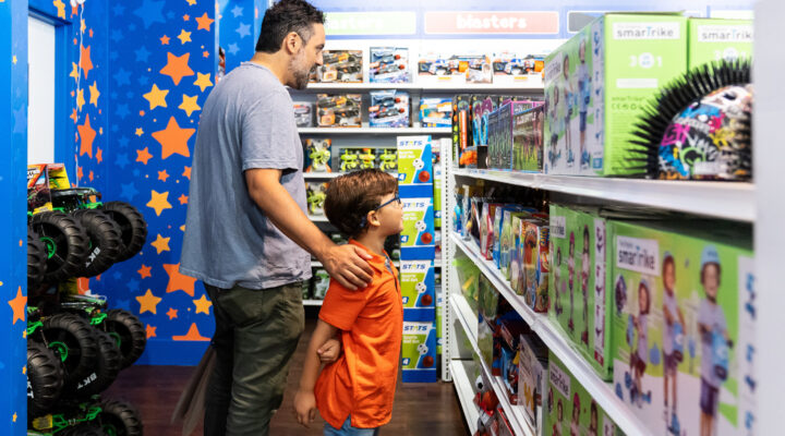 A young boy and his father browsing toys in a Toys R Us aisle.