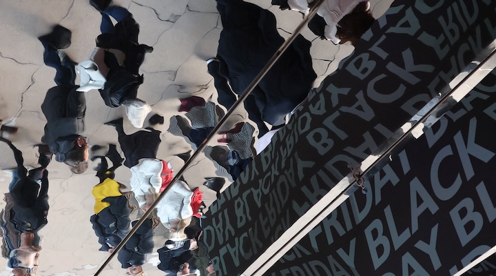 Shoppers are reflected as they pass an advertisement for the Black Friday sales event.
