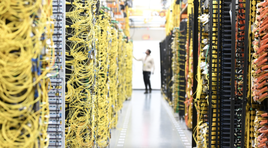 A man standing between walls covered in computer wires.