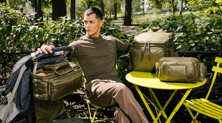 A young man surrounded by Caraa bags sitting on a park bench.