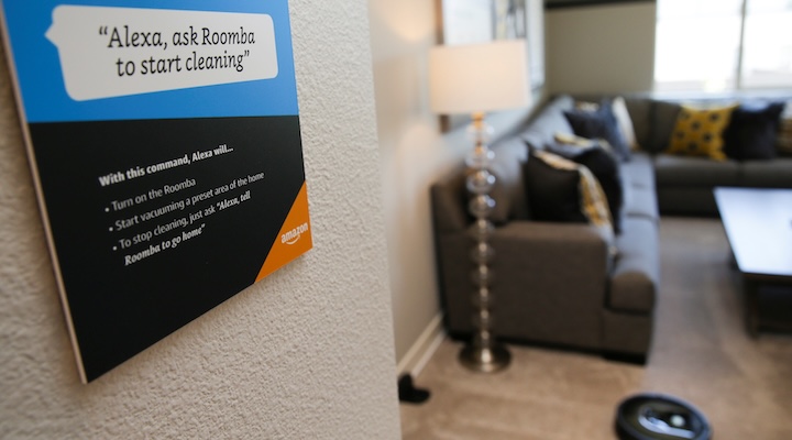 Prompts on how to use Amazon's Alexa personal assistant are seen as a wifi-equipped Roomba begins cleaning a room in an Amazon ‘experience center’
