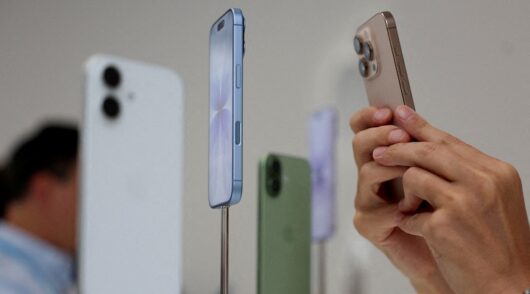 A person uses a phone to capture iPhones on display during Apple's event