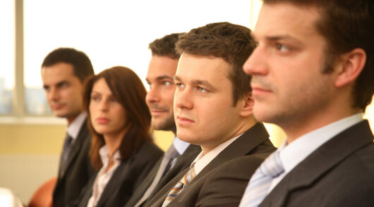 Several executives in a boardroom with serious expressions on their faces.