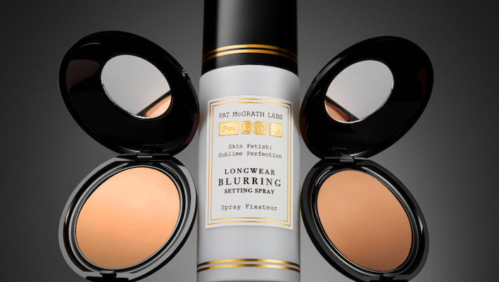 A close-up shot of several Pat McGrath Labs products, including a setting mist and two face powders.