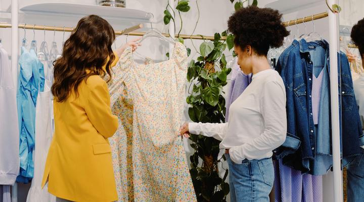 Two women browsing through a rack of clothes.