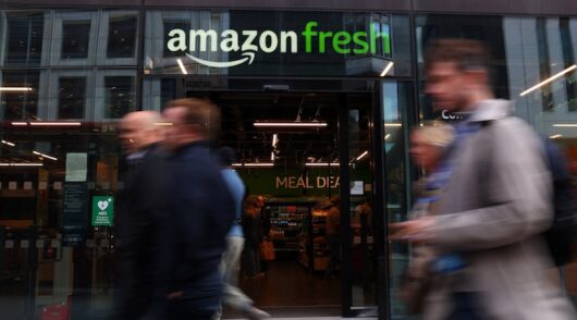 People walk past an Amazon Fresh convenience grocery store in London