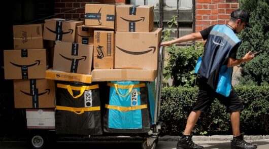An Amazon delivery worker pulls a delivery cart full of packages during its annual Prime Day promotion in New York City