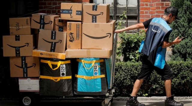 An Amazon delivery worker pulls a delivery cart full of packages during its annual Prime Day promotion in New York City