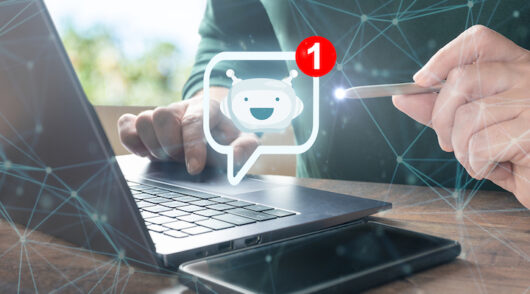 A man working on his laptop with a digital emoticon of a smiling face next to him.