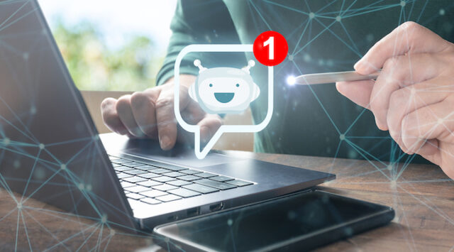 A man working on his laptop with a digital emoticon of a smiling face next to him.