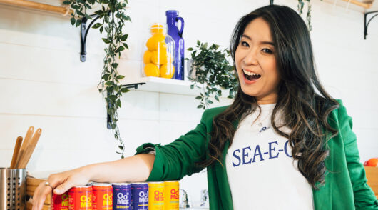 Oomee founder Alissa Miky standing in a kitchen next to multiple drinks.