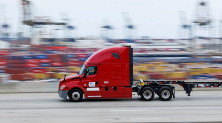 Red truck driving through shipping port.