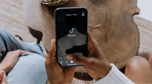 Person holding phone with TikTok app.