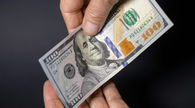 Hands exchange a US $100 bill