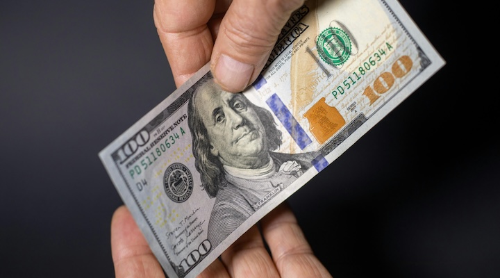 Hands exchange a US $100 bill