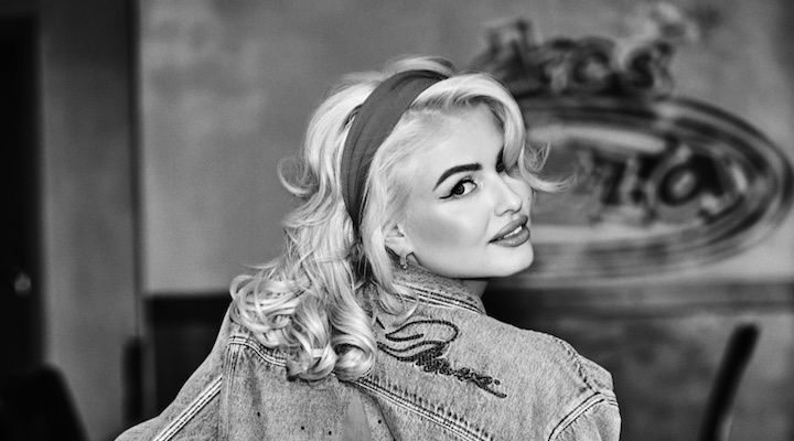 A black-and-white shot of a blond model wearing a denim jacket from Guess’s Marilyn Monroe collection.