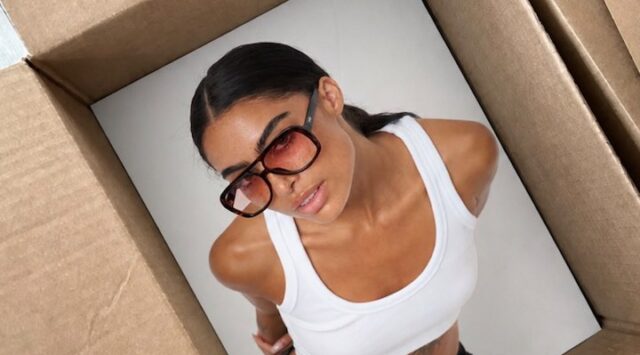 A female model wearing a pair of Otra glasses and a white tank top.