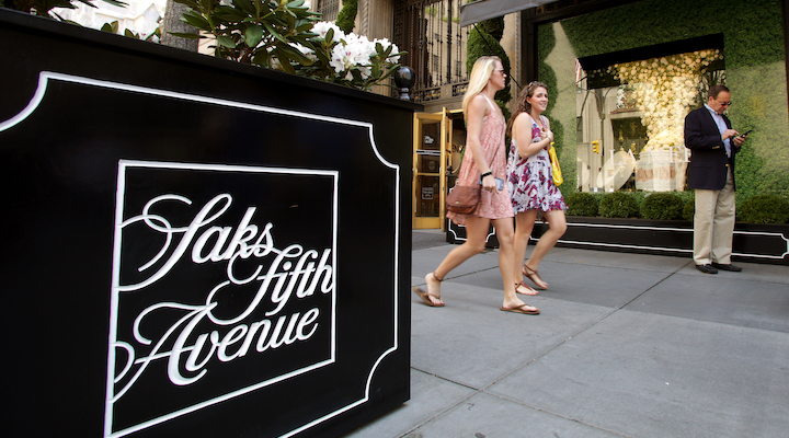 Several young women walking in front of a Saks Fifth Avenue store.