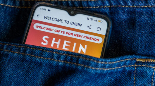 A phone inside of a jeans pocket showcasing Shein’s website.