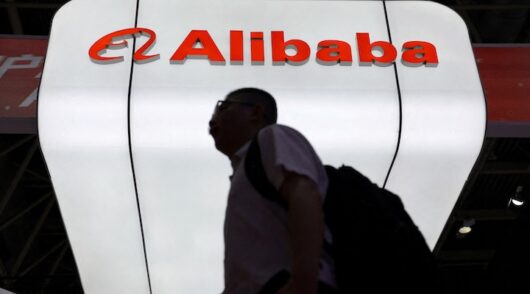 A man walks past the Alibaba logo