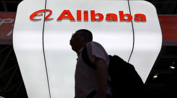 A man walks past the Alibaba logo
