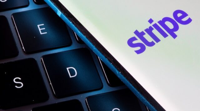 A smartphone with the Stripe logo is placed on a laptop in this illustration