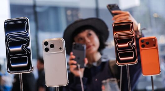 A woman takes a selfie with iPhones inside the Apple store in Beijing's Sanlitun area as the new iPhone 17 series smartphones go on sale in Beijing