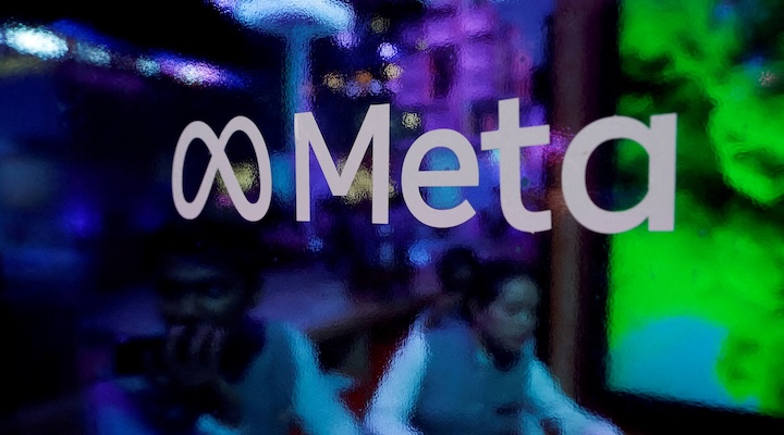 People are seen behind a logo of Meta