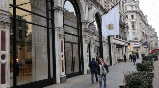 People walk past an Apple store in London
