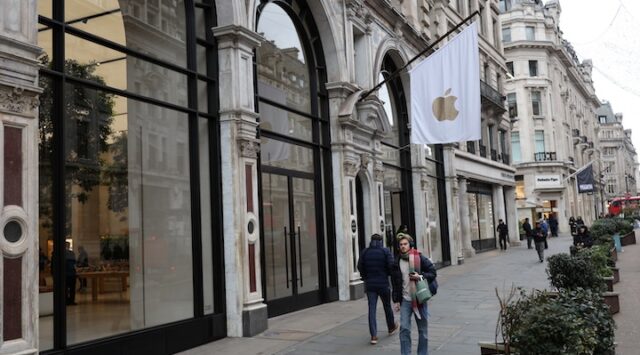 People walk past an Apple store in London
