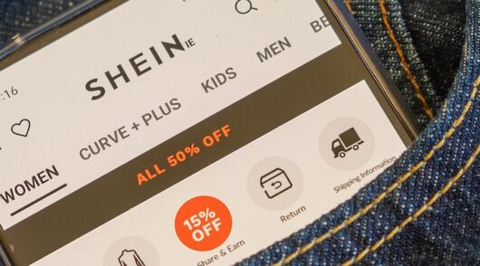 A smartphone in a jean pocket with the Shein website on display.