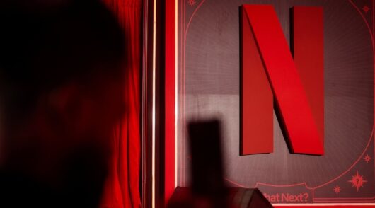 A man takes a photograph next to a Netflix logo during an event in Mumbai, India